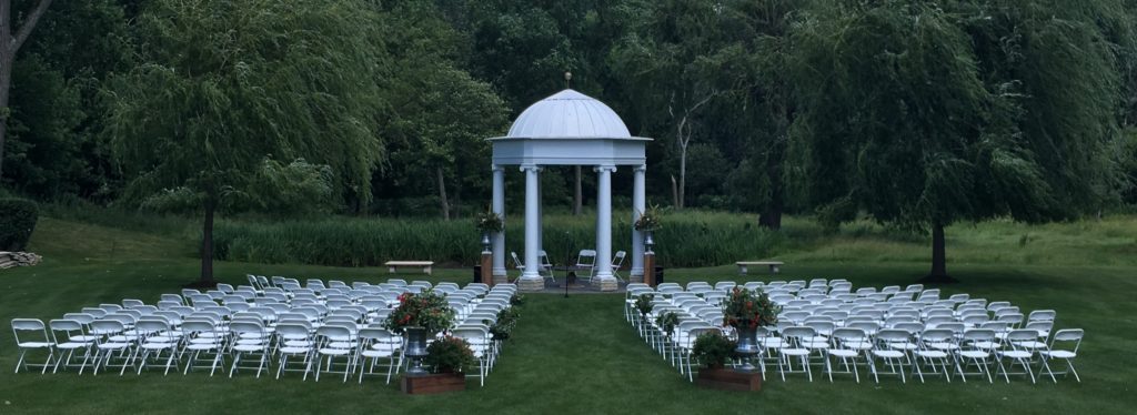 wedding ceremony with white chairs and gazebo