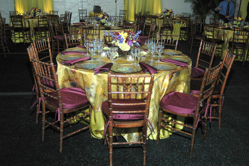 wood-colored chiavari chairs at formal event with gold table cloths and formal table setting